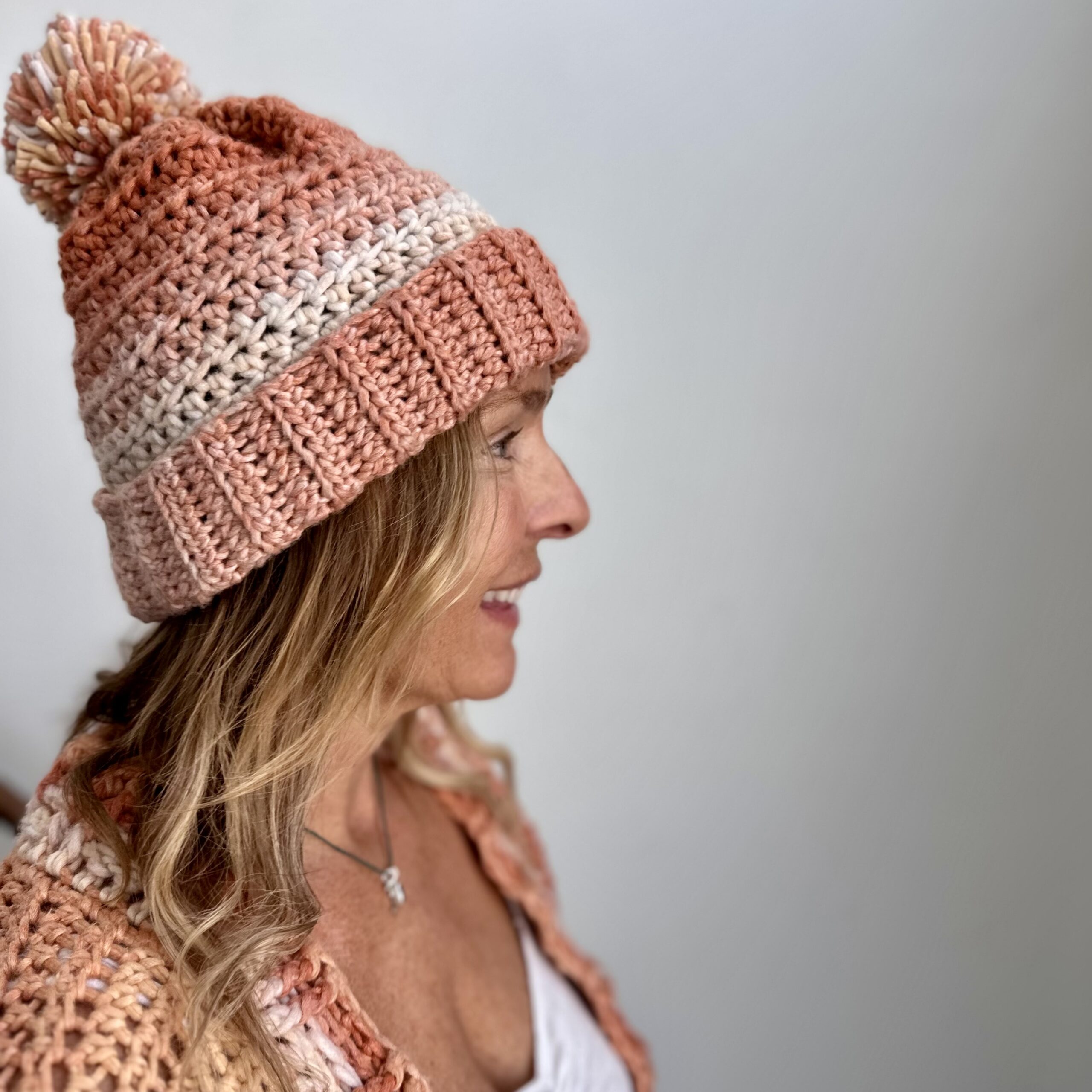 a smiling woman wearing a handmade crochet beanie