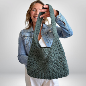 a woman holding a granny square bag