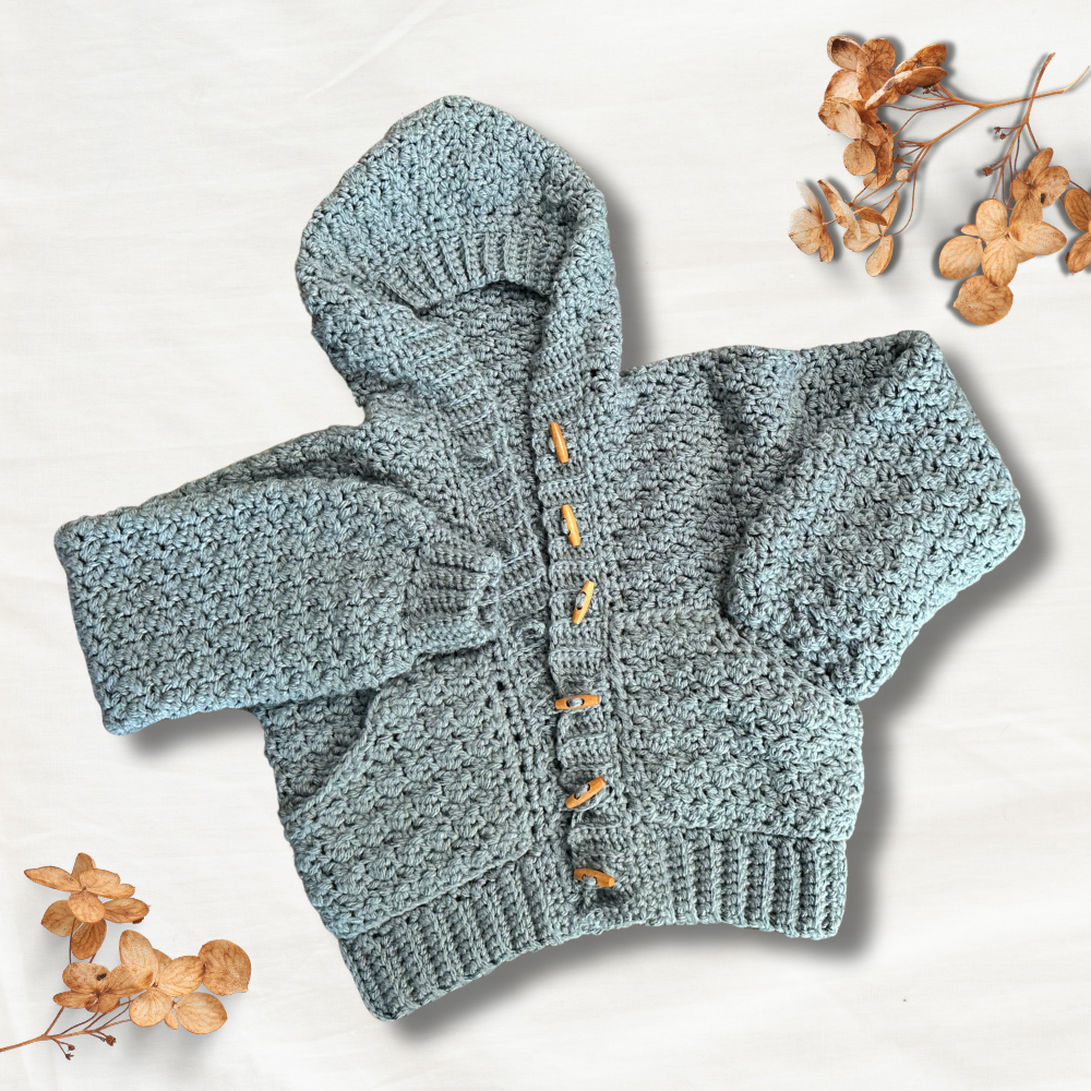 a handmade crochet cardigan laying on a table