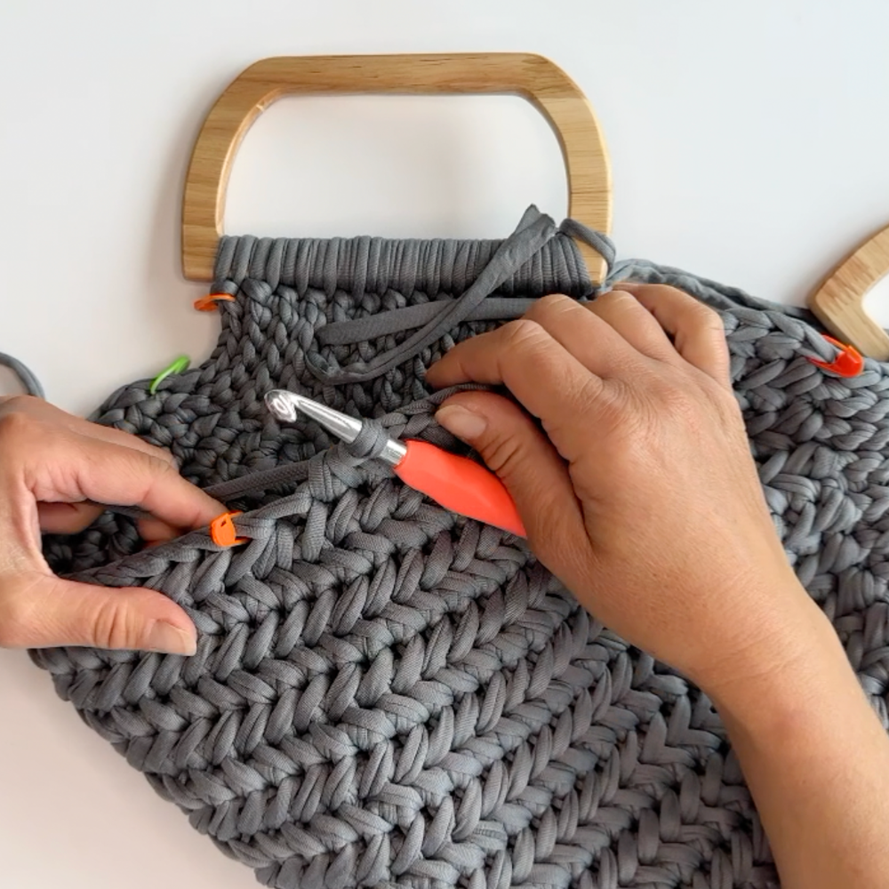 a woman making a crochet bag