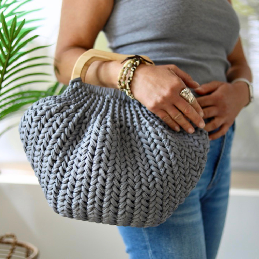 a woman holding a crochet bag