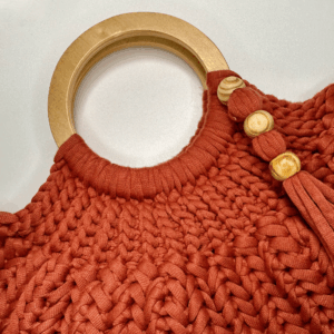 Free crochet bag patterns with a crochet bag with wooden handle laying on a table