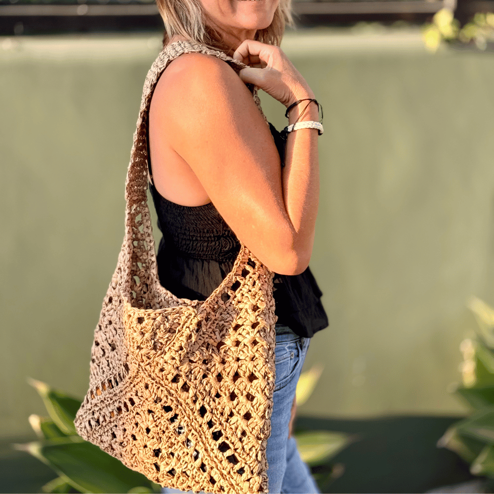 a woman holding a raffia crochet bag